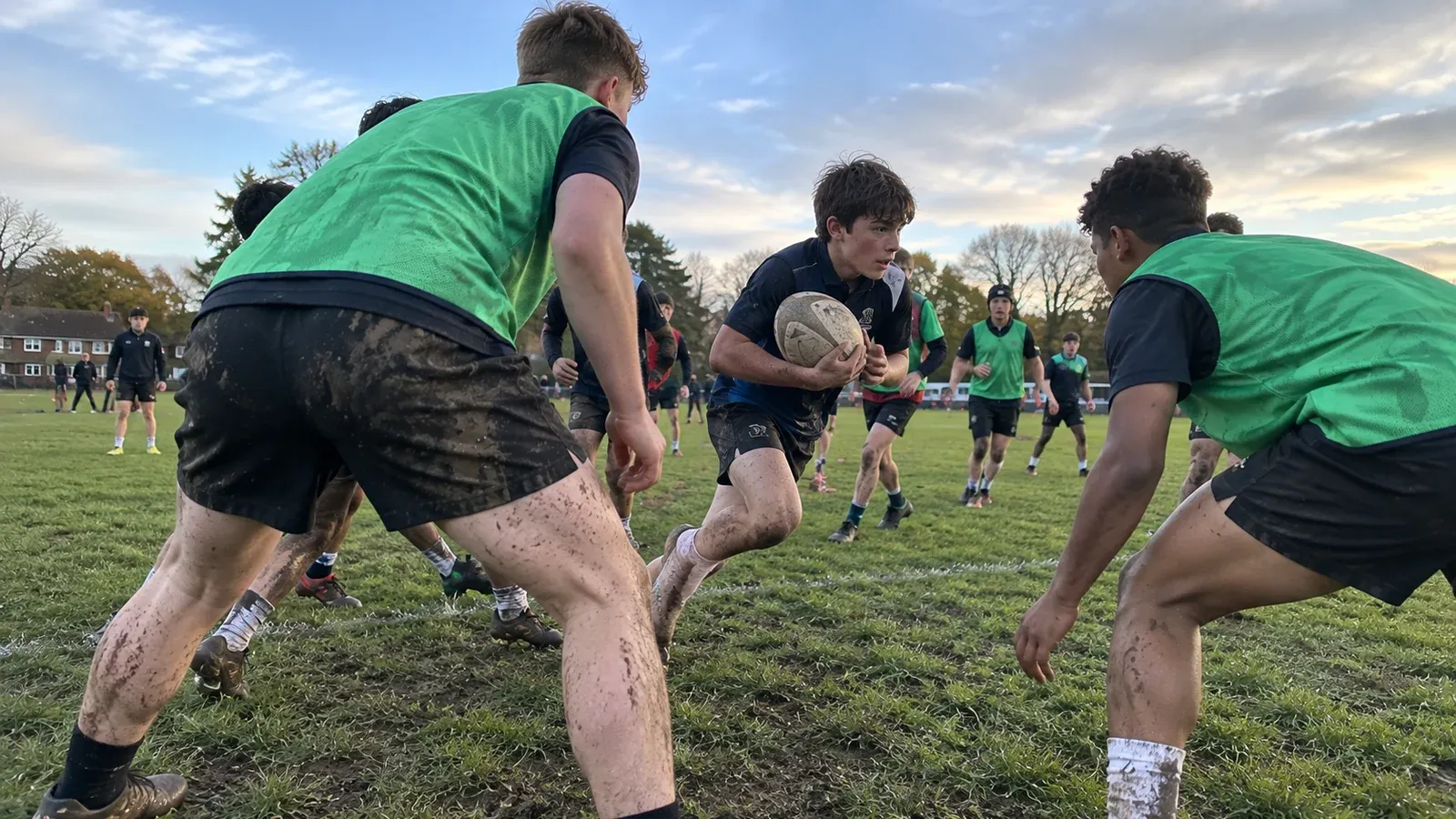 Young rugby players of different builds competing during a muddy community training session